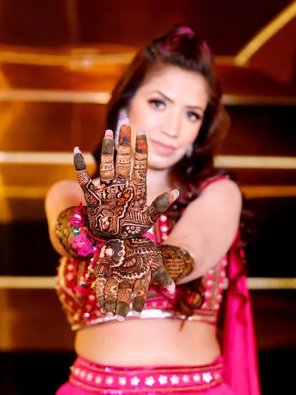 A close-up shot focusing on the bride's intricate Mehndi design. The blurred background makes the henna art pop.