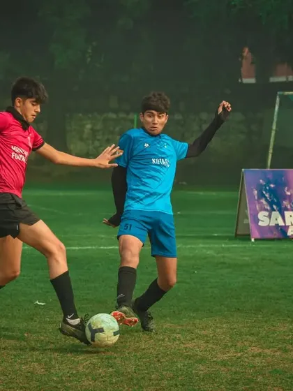 Two young athletes compete for the ball during a night game at the Pride Cup, showing their dedication.