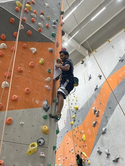 A climber reaches for a high hold on one of our taller routes, demonstrating the endurance required for top-roping.