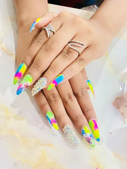 This is the level of artistry you can achieve. This set features advanced stiletto nail extensions with a vibrant tie-dye color blend, intricate floral details, and full-coverage pearl embellishments, demonstrating complex application and design skills.