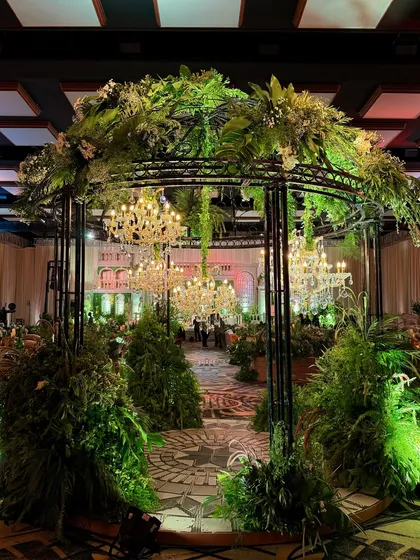 An enchanted garden brought indoors. We transformed this ballroom with lush green arches and a canopy of chandeliers, creating a wedding space that felt both organic and opulent.
