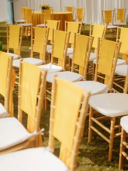 A wider view of the guest seating, showing how the rows of chairs with yellow sashes create a visually appealing pattern on the green lawn, leading towards the main event area.