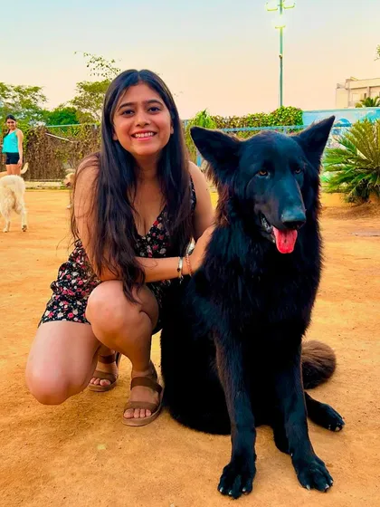 A visitor posing with a majestic black German Shepherd, one of the many breeds you can interact with.