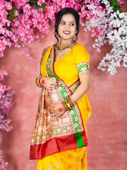 A stunning portrait against a floral backdrop. The mom-to-be wears a bright yellow saree with a red border, creating a vibrant and joyful image that celebrates both nature and tradition.