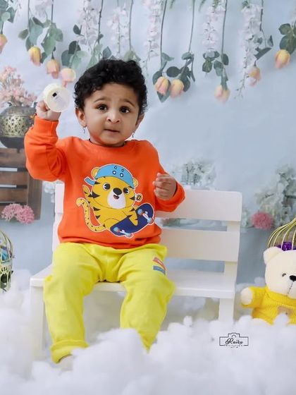 A toddler in a tiger-print sweater sits with his teddy bear friends in our snow-themed studio. It's a playful and cozy scene for a winter-inspired shoot.