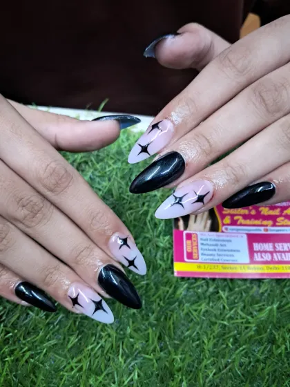 A close-up of these edgy stiletto nails with a sheer base and bold, black hand-painted star designs.