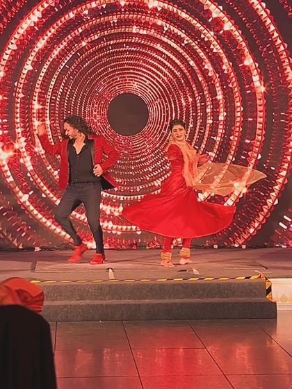 A joyful action shot from a live duet performance on a grand stage.