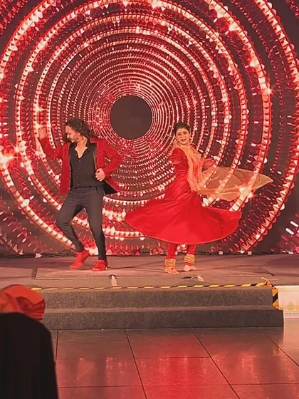 A joyful action shot from a live duet performance on a grand stage.