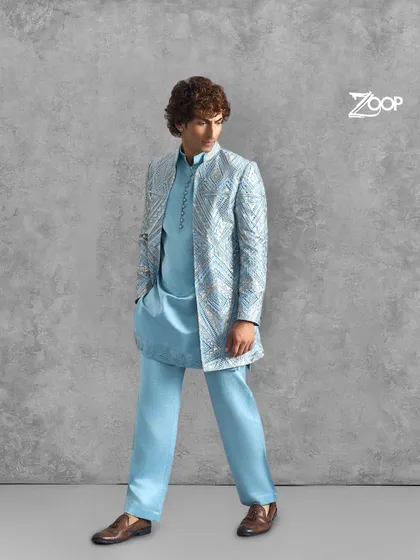 An elegant light blue kurta set with a shimmering, patterned jacket. This outfit is perfect for a wedding guest or for a groom's pre-wedding function, offering a blend of modern style and traditional grace.