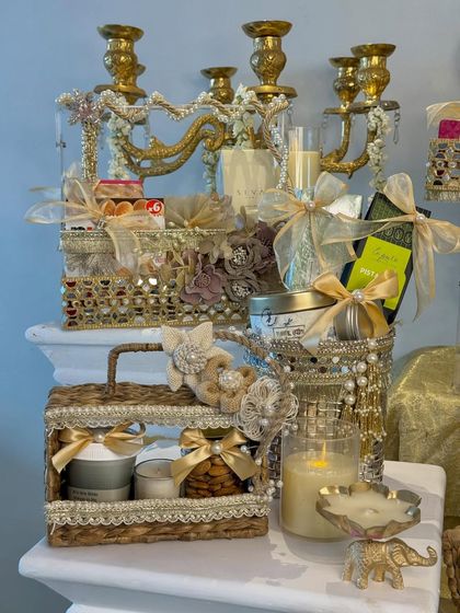 A glimpse of the smaller, coordinated gift hampers from the collection, featuring candles, treats, and beautiful packaging with gold ribbons and floral accents.