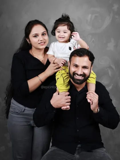 A fun family photo with the baby enjoying a ride on dad's shoulders. The textured grey backdrop adds a modern and sophisticated touch.