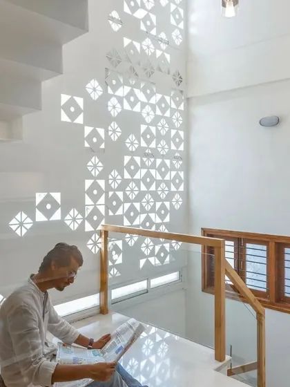 The light filtering through this patterned screen creates a living, changing artwork on the wall.