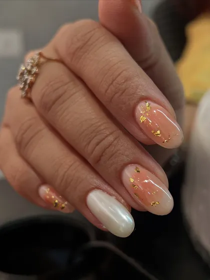 An ombré nail set with a twist. We combined a peachy ombré with gold flakes and a solid pearl chrome accent nail.