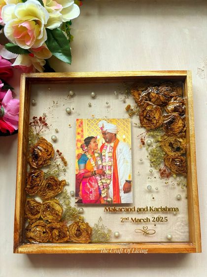 This wooden frame features a simple and elegant layout, with preserved flowers artfully placed in the corners, drawing the eye towards the couple's photo in the center.