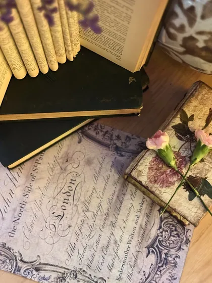 A beautifully styled detail shot with vintage books, calligraphy prints, and small floral touches, evoking a sense of romance and literary charm.