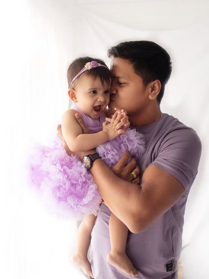 A happy, candid moment between a father and his laughing daughter during her first birthday shoot.