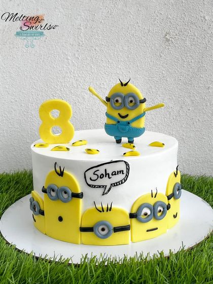 Bello! This fun Minions cake is sure to bring a smile to anyone's face. The cake is decorated with a crowd of mischievous minions and topped with a cheerful, handmade fondant minion figure.