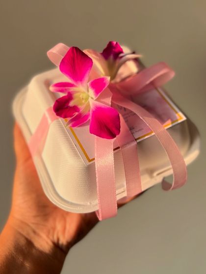 Another beautiful gift-wrapping option featuring a pink ribbon and a fresh orchid, adding a touch of exotic elegance to your bento cake gift.