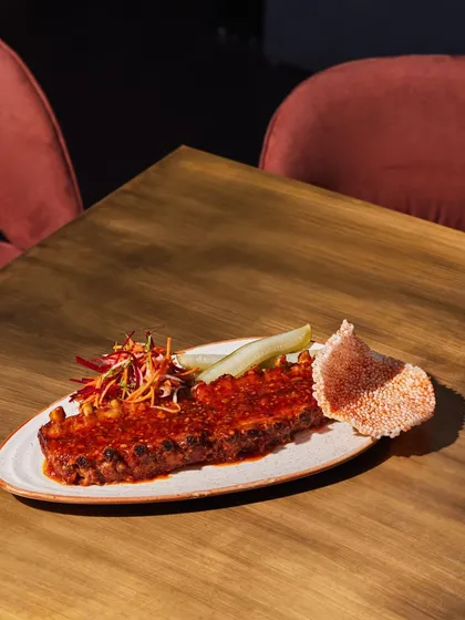 Our tender Baby Back Ribs, glazed in a savory sauce and served with a side of pickled cucumber. This dish is a modern take on a classic favorite, perfect for any meat lover.