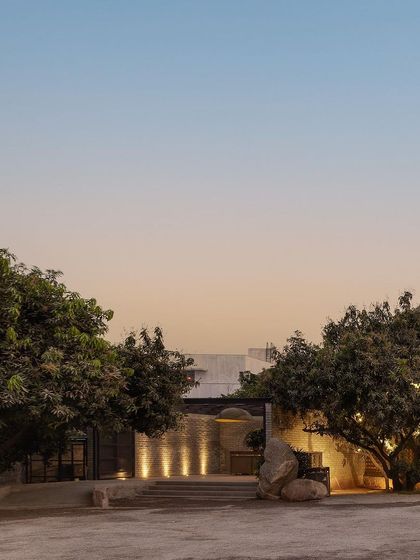 The entrance to Zero40 Brewery at dusk, framed by two large mango trees. The landscape design creates a welcoming and relaxed atmosphere, setting the tone for the leisurely experience inside.