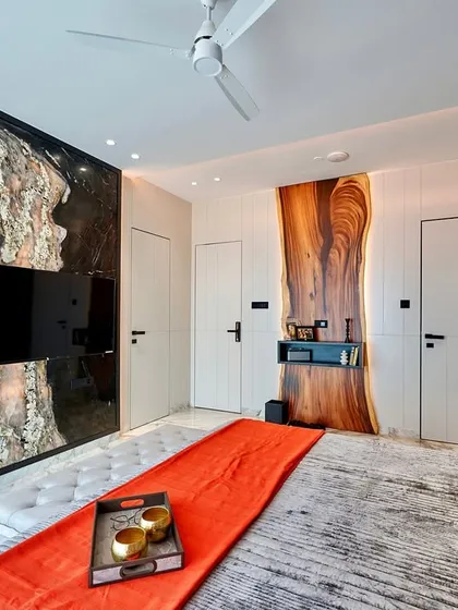 We love using natural materials in unexpected ways. This bedroom features a TV panel made from a unique stone slab and a desk area highlighted by a live-edge wood piece, creating a design that is both rustic and modern.