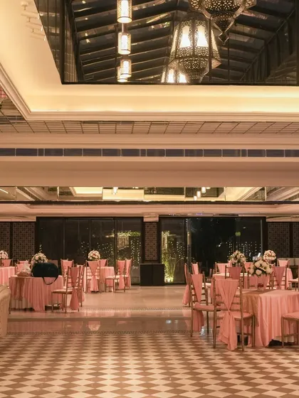 The indoor banquet hall decorated in sync with the outdoor wedding theme. Pink table linens and chair drapes continue the color story, creating a seamless transition for guests.