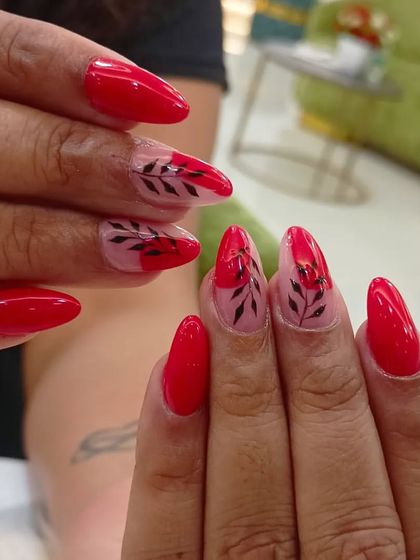 A beautiful combination of solid glossy red nails and sheer accent nails with delicate black leaf illustrations.