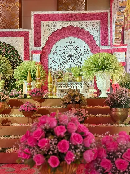 An enchanting symphony of blooms, hues, and traditional grandeur. The foreground of vibrant pink roses leads the eye towards the intricately detailed stage, creating depth and richness. 🌸❤️