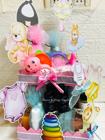 A fully assembled luxury baby shower hamper, bursting with toys, baby care products, and decorative cutouts.