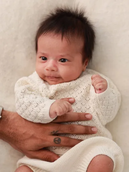 A father's hand gently rests on his newborn's tummy. A simple, loving gesture that speaks volumes.