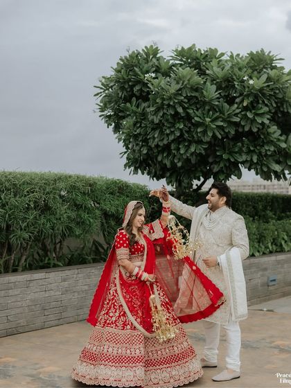 A playful and romantic outdoor portrait, with the groom gently holding the bride's kalire as they share a dance.