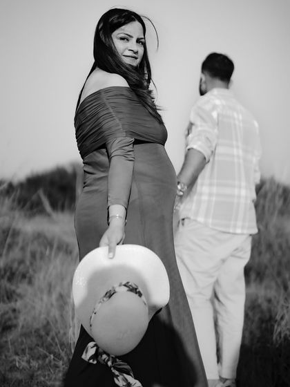 A stylish black and white portrait. The mom-to-be looks over her shoulder as her partner walks away, creating a sense of narrative and emotion.