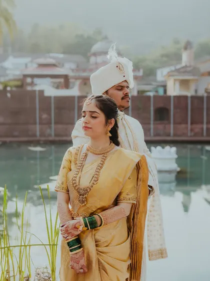A serene portrait of the couple standing by a traditional Goan temple pond, a moment of peace on their wedding day.