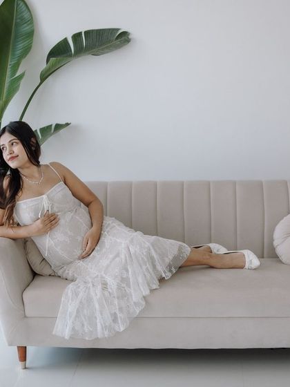 A full-length shot of a pregnant mother relaxing on a couch by the window, using beautiful natural light.