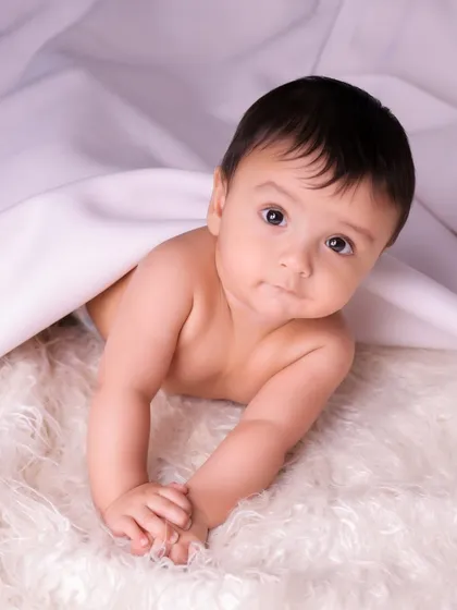A curious baby peeks out from under a blanket. These spontaneous moments often make for the most cherished and authentic portraits.