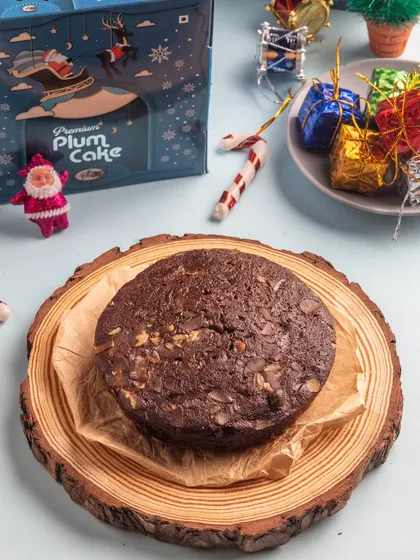 Our premium plum cake, presented on a rustic wooden slice, highlighting its rich texture and nutty topping.