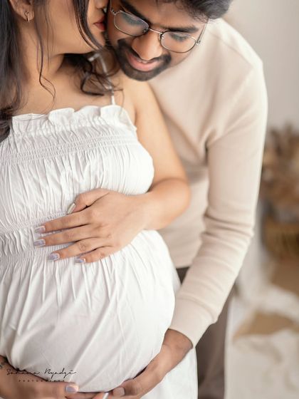 A close-up filled with tenderness. This shot focuses on the couple's hands on the baby bump and the dad-to-be whispering to his wife, a truly intimate moment.