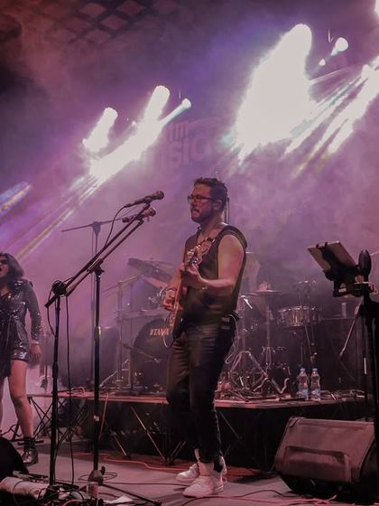 A wide shot of the band on stage, bathed in purple light. This image captures the epic, concert-like feel of our performances.