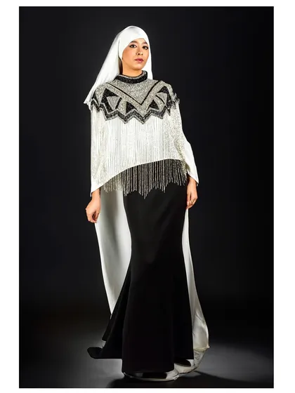 A powerful, direct pose that showcases the full impact of this modern, modest ensemble. The strong contrast between the black skirt and the white, embellished top creates a striking graphic quality.