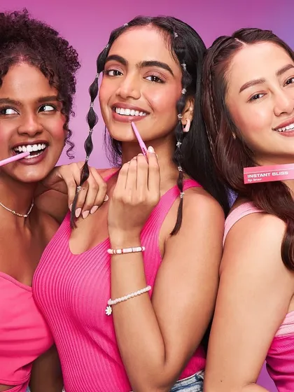 A cheerful beauty shot with models applying lip tints. The makeup is fresh, youthful, and glowing, perfectly capturing the fun and accessible nature of the beauty brand.