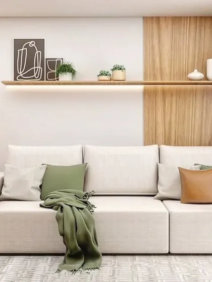 This living room features a comfortable white sofa with green and brown cushions. The floating shelf with backlighting is perfect for displaying decor.