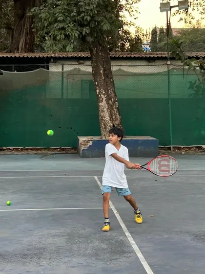 A young player focuses on his forehand, demonstrating the concentration and technique we instill in our students from an early age.