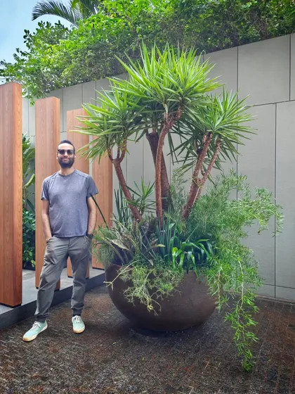 This is what we call "Contained Maximalism." For this installation, we packed a single, oversized pot with a multi-headed Yucca tree and an abundance of cascading plants. It creates a powerful, self-contained landscape that makes a huge impact, seen here with our co-founder Angud.