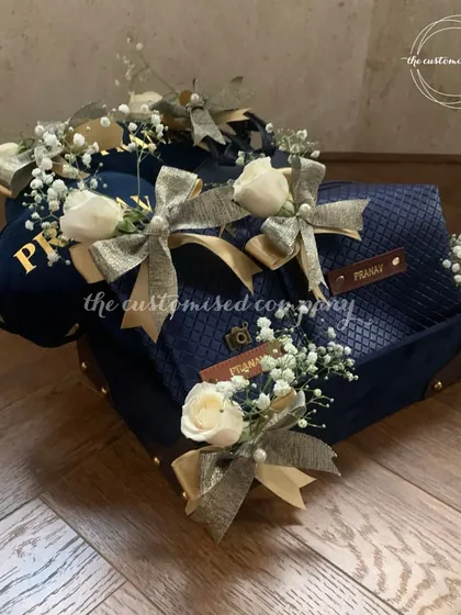 A closer look at our beautifully decorated travel hamper. The personalized cap, passport cover, and other accessories are individually wrapped with delicate ribbons and flowers for a luxurious unboxing experience.