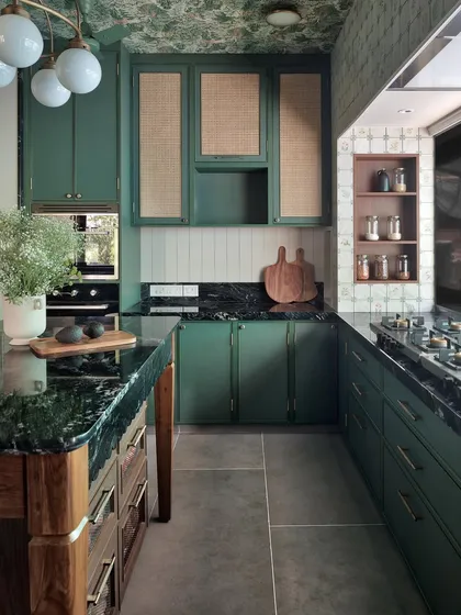 This wide shot shows the U-shaped layout of the green kitchen, designed for maximum efficiency. The island provides extra workspace and storage, while the patterned ceiling adds a whimsical touch.