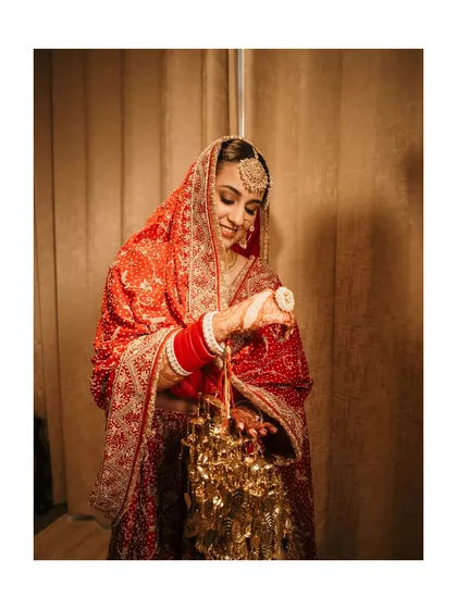 The bride smiling as she looks at her kalire. This is a classic Punjabi wedding tradition, and we love capturing the joy and anticipation associated with it.