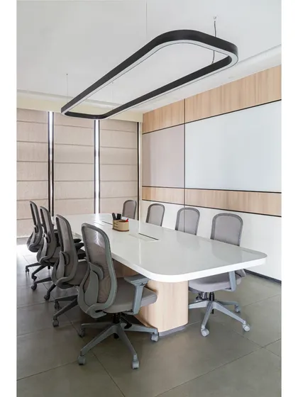 The main conference room at Thalia, designed for focus and clarity. The space features a large whiteboard wall, clean lines, and a modern overhead light fixture that illuminates the entire table.