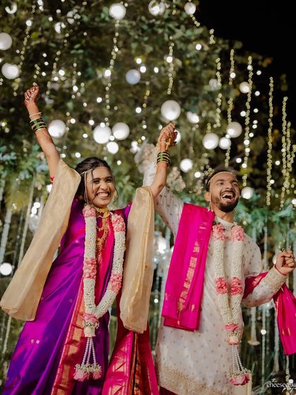 The couple dancing with joy, a perfect candid moment from their Maharashtrian wedding.