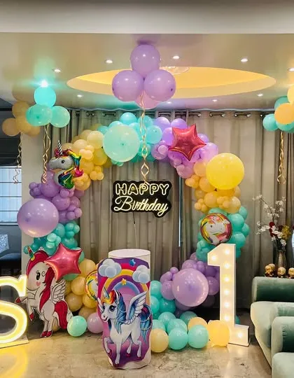 Even in a cozy living room, I can create a magical unicorn-themed party. This home setup features a circular balloon arch, unicorn cutouts, marquee letters, and ceiling balloons to transform the space.