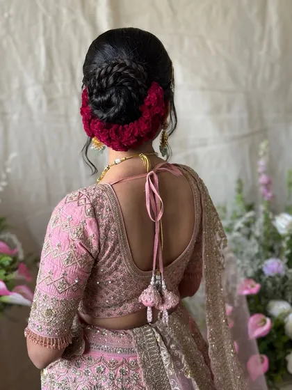 A stunning bridal bun with a braided detail and a vibrant red floral arrangement. This hairstyle is bold, beautiful, and makes a statement.